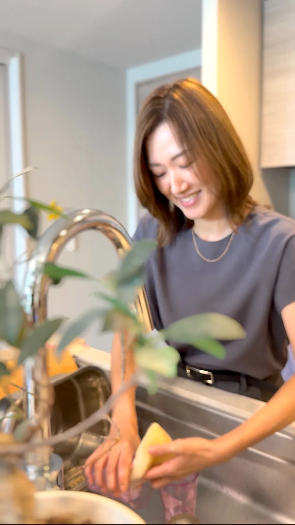 キッチンで家事をしながら微笑む保護者