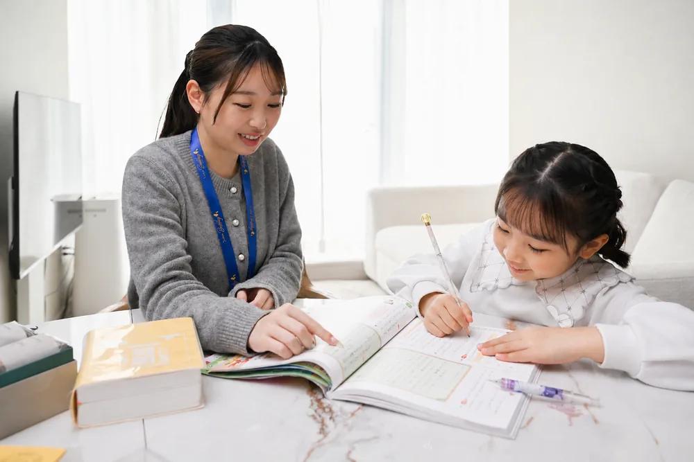 子どもの隣でノートを指しながら宿題をサポートするBuddy